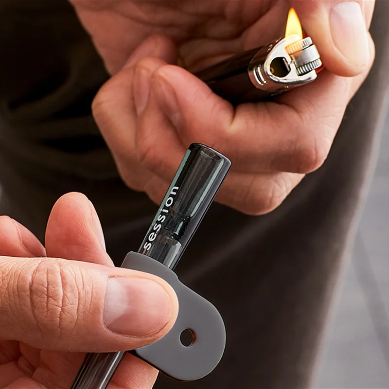 a man holding a sessions chillum in his hand with a stuck lighter